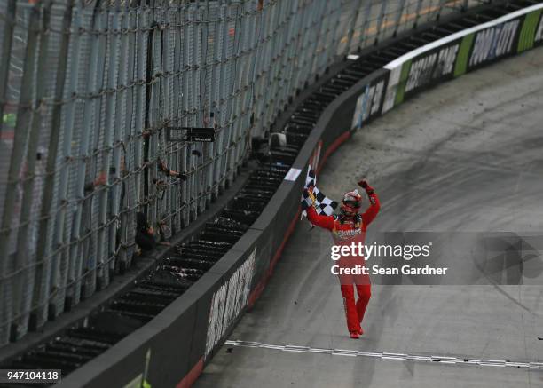 Kyle Busch, driver of the Skittles Toyota, celebrates with the checkered flag after winning the rain delayed Monster Energy NASCAR Cup Series Food...