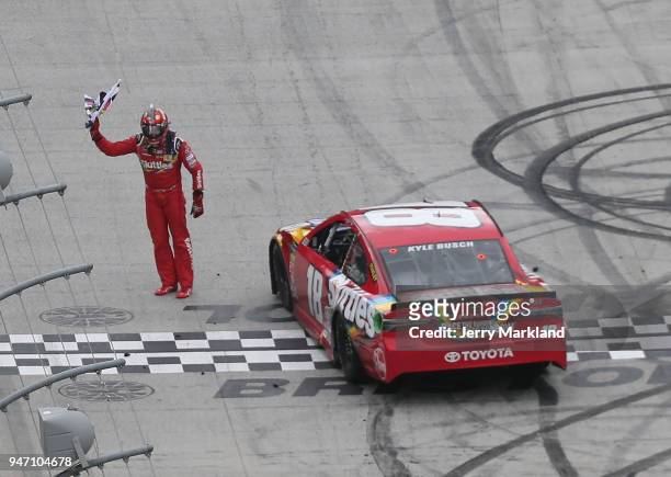 Kyle Busch, driver of the Skittles Toyota, celebrates with the checkered flag after winning the rain delayed Monster Energy NASCAR Cup Series Food...
