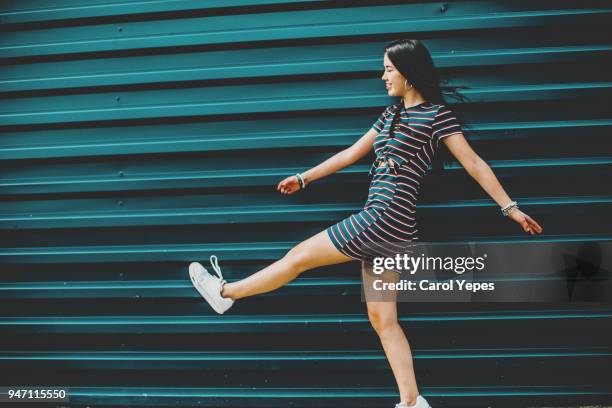 happy brunette young woman walking on street against blue wall - summer frock stock pictures, royalty-free photos & images