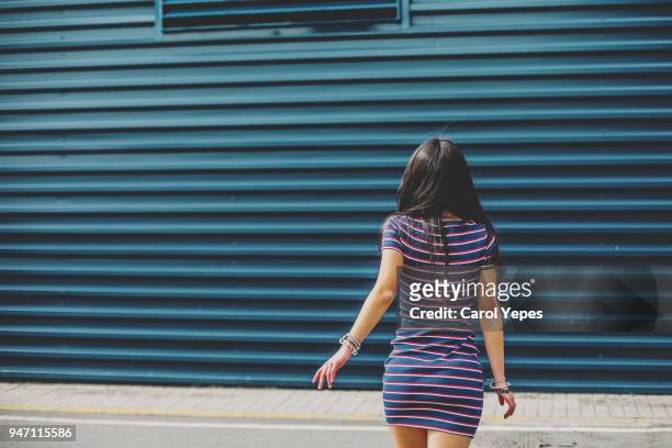 mid section brunette teenager walking away against blue wall - beautiful hips photos et images de collection