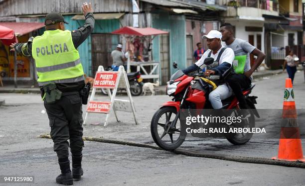 Police officer stops two men on a motorbike druing a patrol in Tumaco, a municipality in the Colombian department of Narino near the border with...