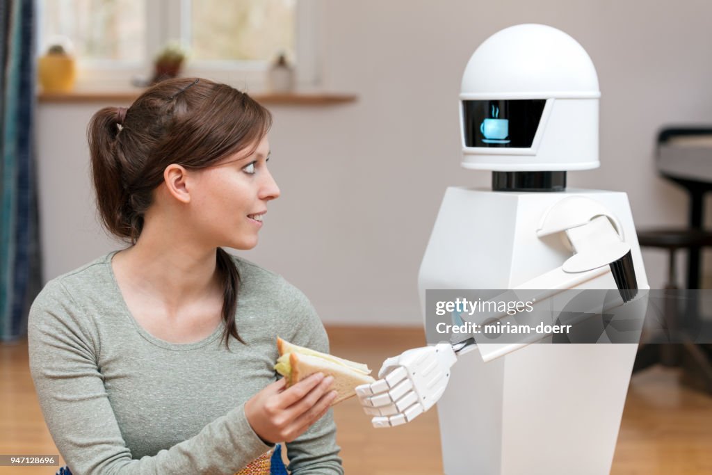 Service-Roboter ist einer Brünette, hübsche Frau einen Sandwich geben, im Wohnzimmer, Anzeige des Haushalts Roboter eine Kaffeepause-symbol