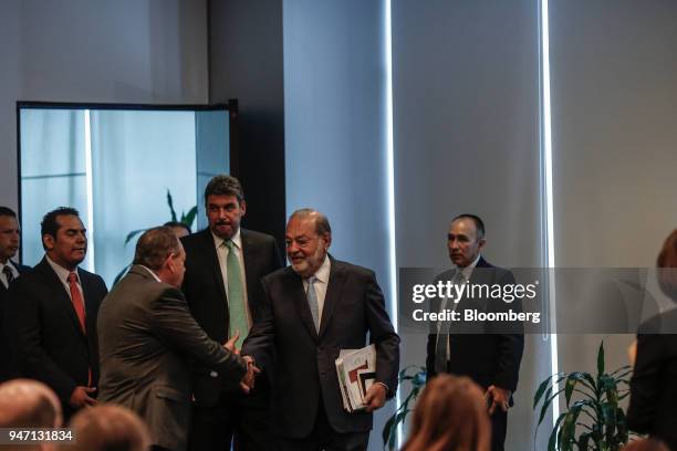 Carlos Slim, chairman emeritus of America Movil SAB, center, shakes hands with an attendee while arriving to speak at a press conference in Mexico...