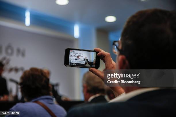 An attendee uses a mobile phone to record a Facebook Inc. Live stream of Carlos Slim, chairman emeritus of America Movil SAB, speaking during a press...