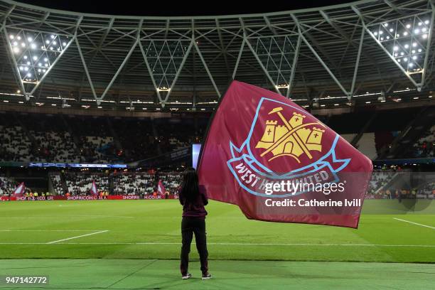 Fan waves a flag during the Premier League match between West Ham United and Stoke City at London Stadium on April 16, 2018 in London, England.