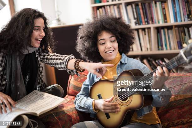 jeune femme, apprendre à jouer de la guitare avec le professeur de musique - party friends home guitar singers photos et images de collection