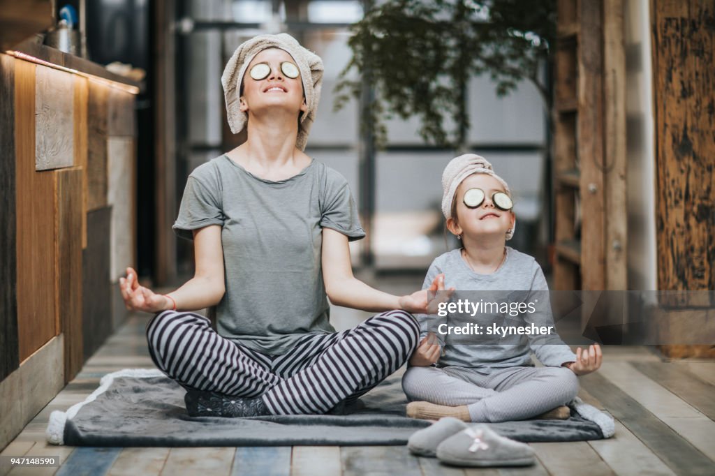 Ontspannen moeder en dochter die Yoga uitoefenen in de ochtend thuis.