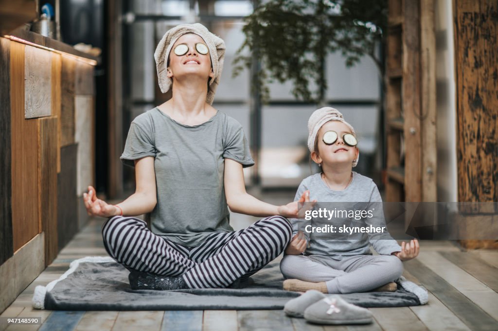 Avslappnad mor och dotter utövar Yoga på morgonen hemma.