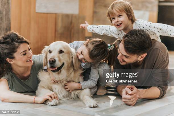 junge glückliche familie genießen mit ihren golden retriever zu hause. - family dog stock-fotos und bilder