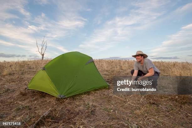 camping jüngling passt ein seil aus seinem zelt - akubra hat stock-fotos und bilder