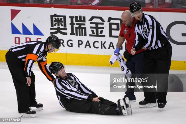 Linesman Steve Barton lays on the ice and is attended to by referee Brian Pochmara , linesman Devin Berg and the Washington Capitals trainer Jason...