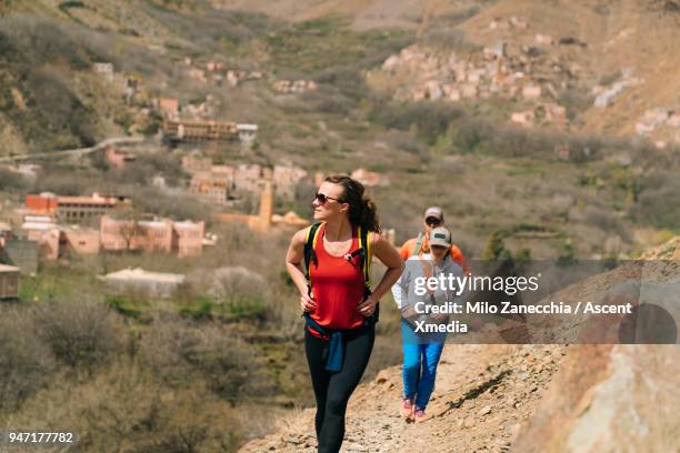 friends hiking  above moroccan villages - montañas atlas fotografías e imágenes de stock