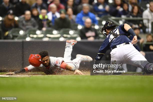 Phillip Ervin of the Cincinnati Reds beats a tag at home plate by Jett Bandy of the Milwaukee Brewers to score a run during the second inning at...