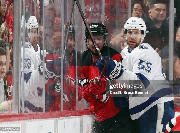 Braydon Coburn of the Tampa Bay Lightning checks Marcus Johansson of the New Jersey Devils into the glass during the first period in Game Three of...