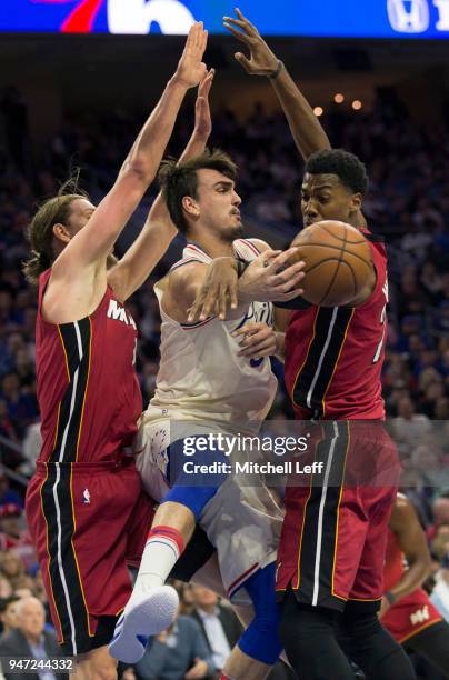 Dario Saric of the Philadelphia 76ers passes the ball around Kelly Olynyk and Hassan Whiteside of the Miami Heat in the second quarter during Game...