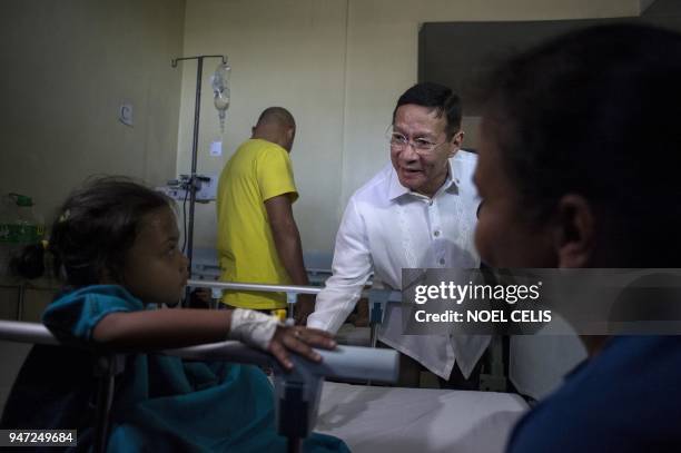 This photo taken on March 5, 2018 shows Philippines' Department of Health Secretary Francisco Duque talking to a dengue patient who has not been...