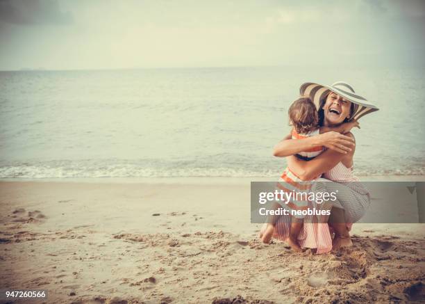 mother and daughter embracing at the beach - retro summer holiday stock pictures, royalty-free photos & images