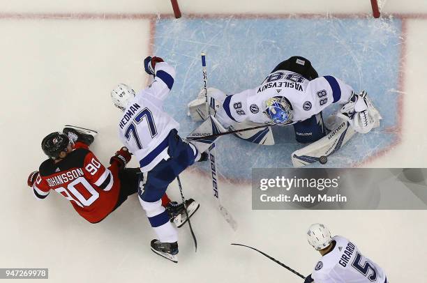 Andrei Vasilevskiy of the Tampa Bay Lightning makes a pad save as Victor Hedman checks Marcus Johansson of the New Jersey Devils in Game Three of the...