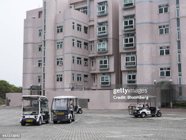 Golf carts stand parked in front of an apartment building in Discovery Bay, a residential project developed by Hong Kong Resort Co., on Lantau Island...