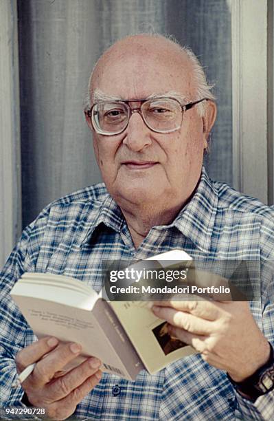 Italian writer Andrea Camilleri fiddling through the book Il teatro illustrato nelle edizioni del Settecento di Carlo Goldoni. 1995