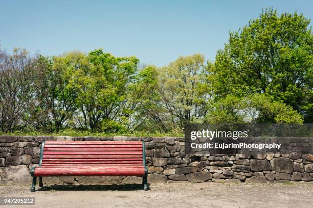 red color bench in the park on a beautiful spring day - park bench stock-fotos und bilder