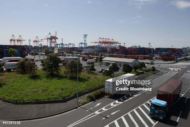 Trucks hauling containers drive past a shipping terminal in Yokohama, Japan, on Monday, April 16, 2018. Japan and China held their first...