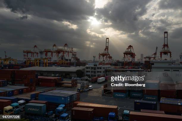 Containers and gantry cranes stand at a shipping terminal at dusk in Yokohama, Japan, on Monday, April 16, 2018. Japan and China held their first...