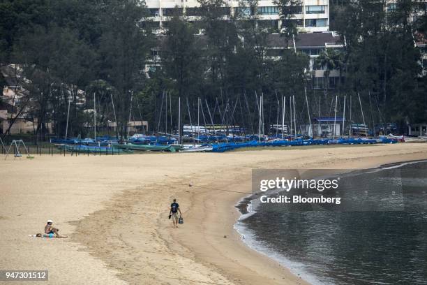Man walks past beachgoers on Tai Pak beach in Discovery Bay, a residential project developed by Hong Kong Resort Co., on Lantau Island in Hong Kong,...