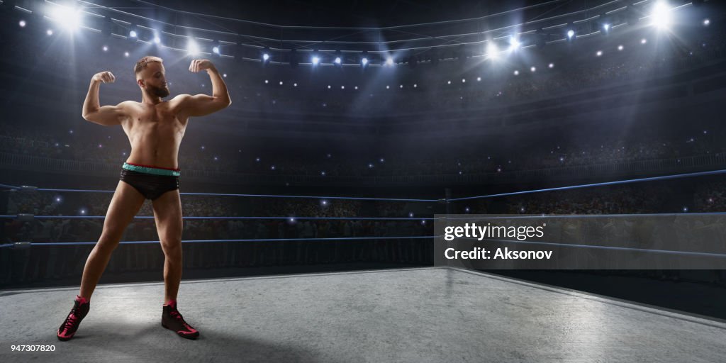 Wrestling show. Wrestler in a bright sport clothes and face mask in the ring