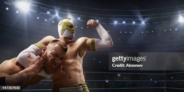 spettacolo di wrestling. due lottatori in abiti sportivi luminosi e lotta con la maschera facciale sul ring - wrestling foto e immagini stock