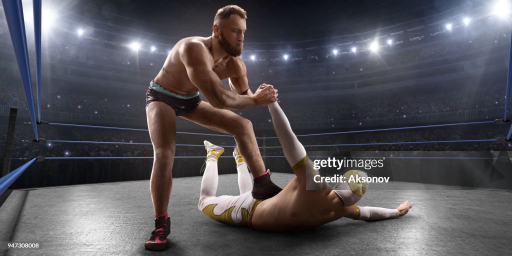 Wrestling show. Two wrestlers in a bright sport clothes and face mask fight in the ring
