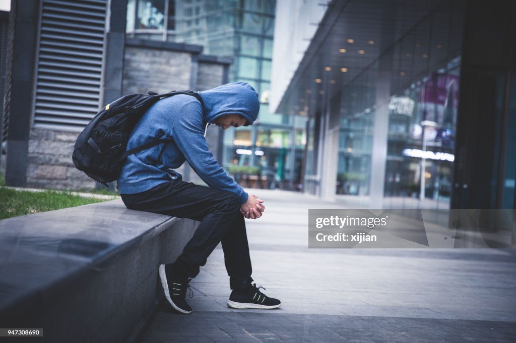 Sad man sitting on city street