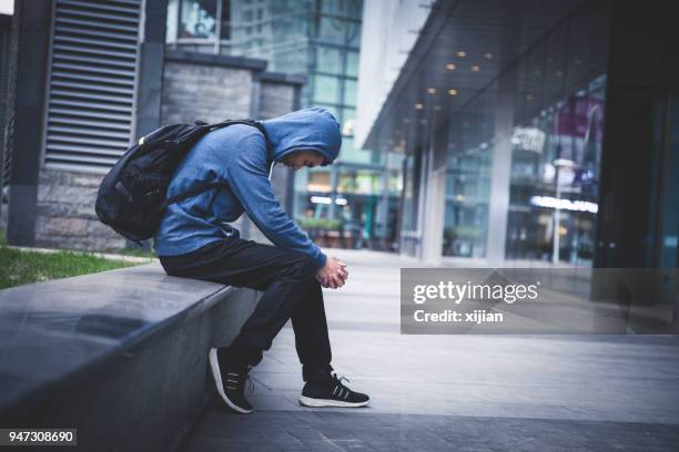 sad man sitting on city street - unemployment stock pictures, royalty-free photos & images