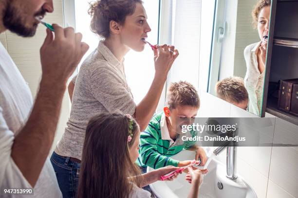 jong gezin samen tandenpoetsen - zustand stockfoto's en -beelden