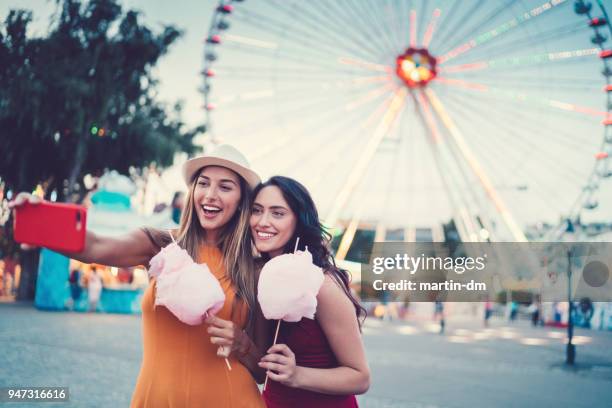 frauen im freizeitpark rosa zuckerwatte essen und nehmen selfie/vlogs - wien österreich stock-fotos und bilder