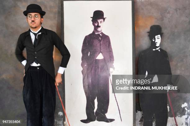 In this photograph taken on April 16 Talin Mavani, a Charlie Chaplin impersonator, checks his appearance in a mirror as he stands next to images of...