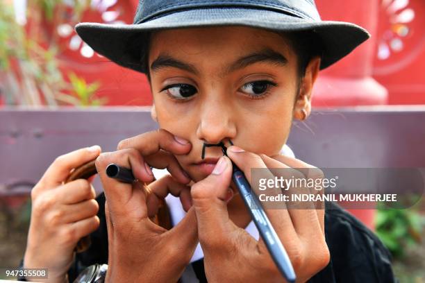 In this photograph taken on April 16 a young Charlie Chaplin impersonator is helped with makeup during an event commemorating the legendary actor's...