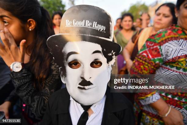 In this photograph taken on April 16 a young Charlie Chaplin impersonator wearing a mask with the face of the actor, poses for a picture during an...