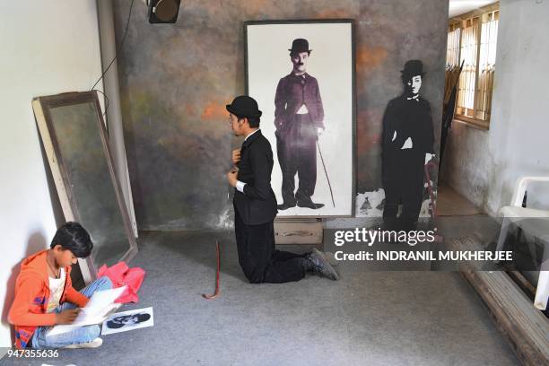 In this photograph taken on April 16 Talin Mavani, a Charlie Chaplin impersonator, checks his appearance in a mirror as a student takes part in a...