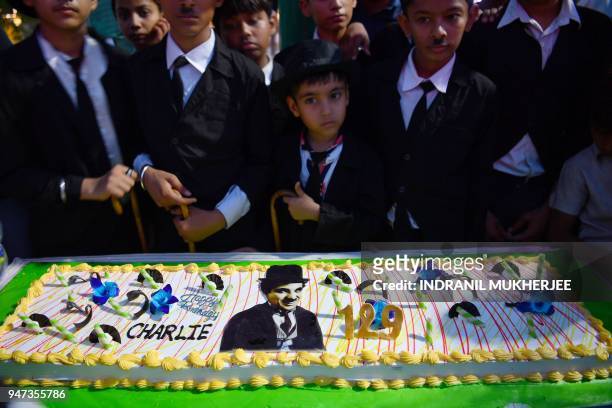In this photograph taken on April 16 young Charlie Chaplin impersonators stand behind a cake during an event commemorating the legendary actor's...