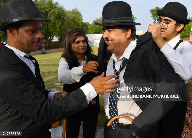 In this photograph taken on April 16 2018, Talin Mavani , a Charlie Chaplin impersonator helps his grandfather Ashok Aswani, founder of the Charlie...