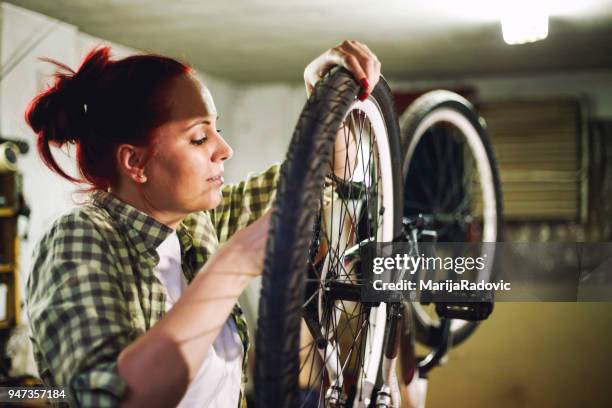 jonge vrouw fiets monteur is het repareren van een fiets in de werkplaats - overtime sport stockfoto's en -beelden