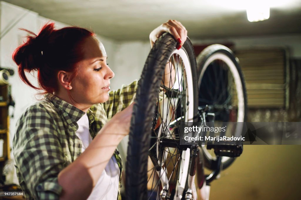 Young woman bicycle mechanic is repairing a bike in the workshop