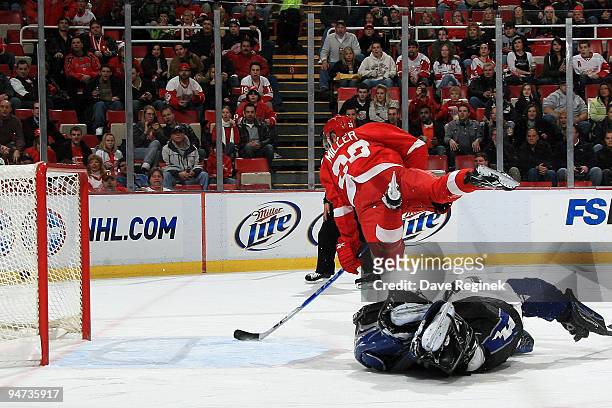 Mike Smith of the Tampa Bay Lightning falls to the ice and Drew Miller of the Detroit Red Wings takes a shot mid-air and scores during a NHL game at...