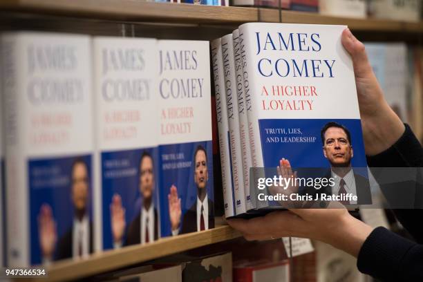 In this photo illustration a Waterstone's employee places copies of Former FBI Director James Comey's book on a shelf as it is released in the UK at...