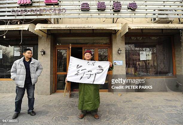 Photo taken on 14 December 2009 shows 46-year-old Lu Daren holding up a banner which reads "nail house" outside a Beijing restaurant he has been...
