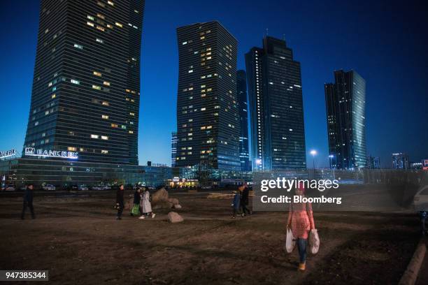 Pedestrians and shoppers walk through a clearing near the Northern Lights towers, left, standing among other residential and commercial buildings...