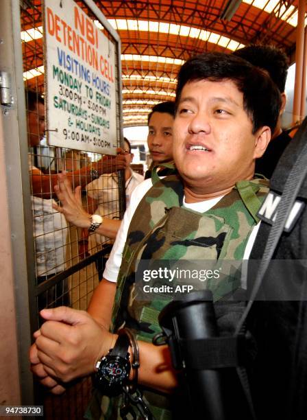 Massacre suspect Datu Unsay Mayor Andal Ampatuan smiles as he is escorted by National Bureau of Investigation agents out of the NBI detention cell to...