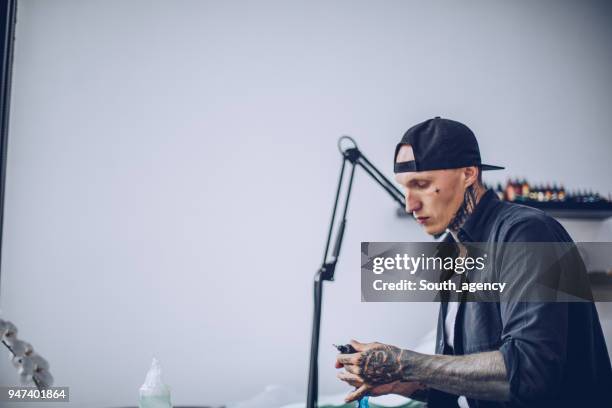 guy preparing tattoo machine for work - surgical suture stock pictures, royalty-free photos & images