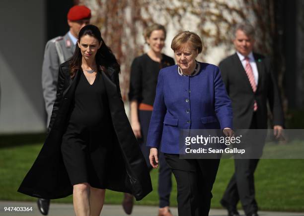German Chancellor Angela Merkel and pregnant New Zealand Prime Minister Jacinda Ardern arrive to review a guard of honor upon Ardern's arrival at the...